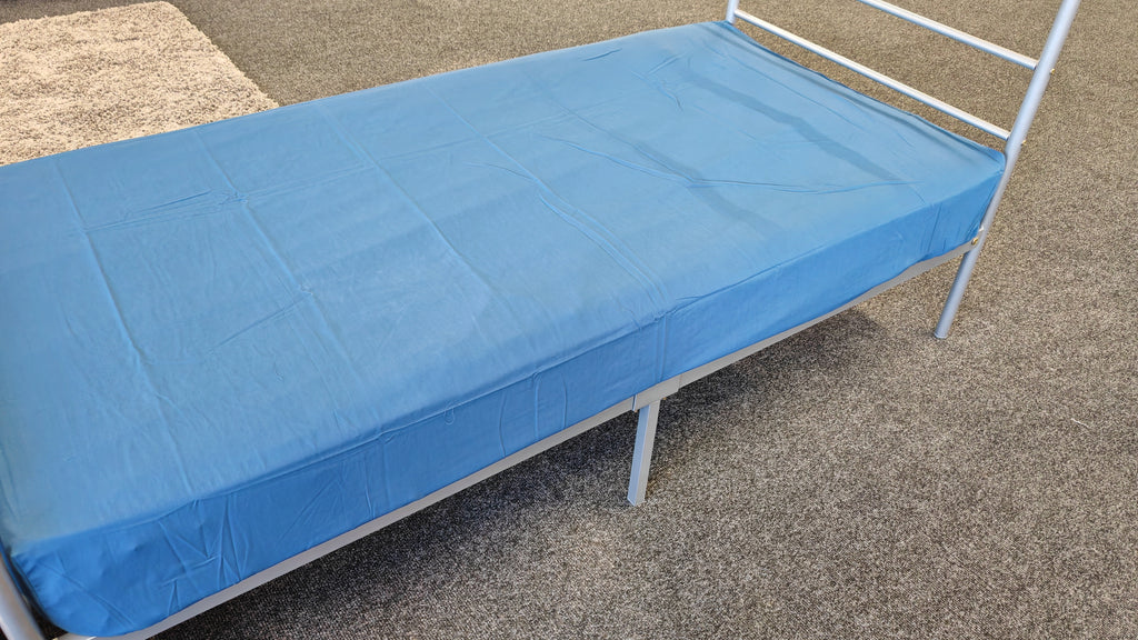 Picture of a dark blue fitted sheet on a metal bed frame. 