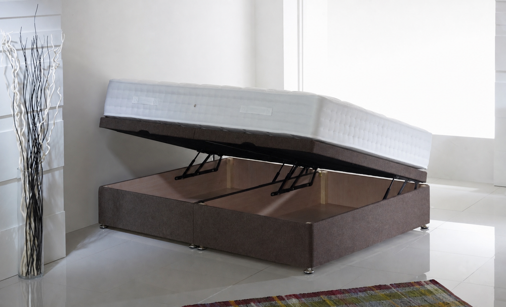 Picture of a side lift single ottoman in a white room with a brown headboard, a rug on the floor and a vase filled with white and black sticks to the side of it