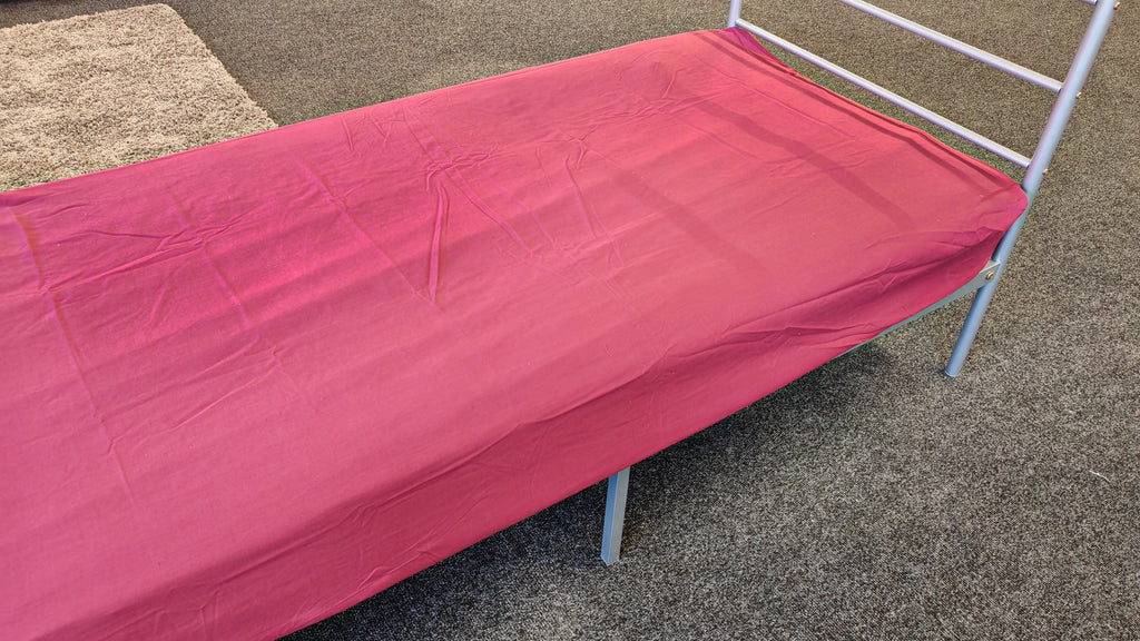 Picture of a wine fitted sheet on a metal bed frame. 